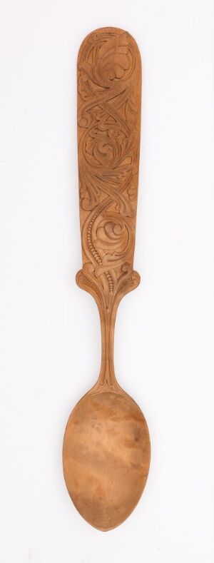  A handcrafted wooden spoon with ornate carvings on the handle, featuring a smooth finish and a warm, brown coloration, presented on a plain light background. Artistname and title are unknown.