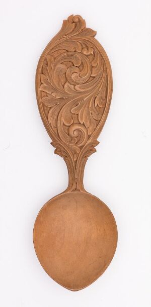  An elegantly carved wooden spoon with an intricate handle featuring organic patterns, displayed against a light, neutral background.