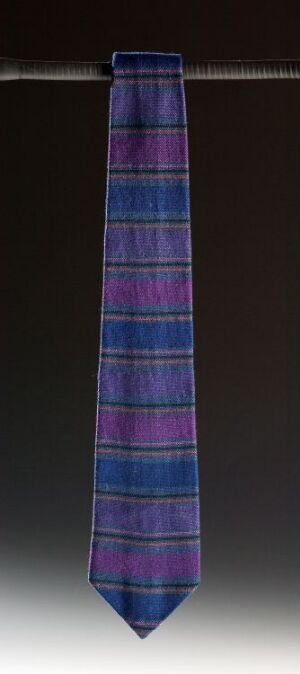  A necktie with a plaid pattern in shades of blue, purple, and pink, hanging against a dark background.