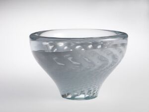  A translucent blue-tinted glass bowl with an etched frosted design featuring swirls and stylized leaf patterns, set against a soft gradient gray background.