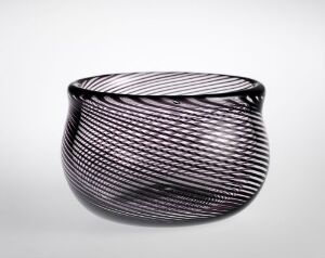 
 A rounded, black glass bowl with thin, white, diagonal lines spiraling around the exterior, against a plain, light background.