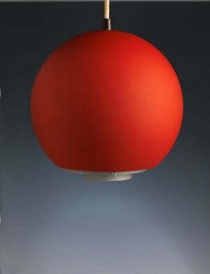  A "Topan (spesialbestilt variant)" pendant lamp by Louis Poulsen & Co, made from lacquered aluminum, displayed against a blue-gray gradient background. The lamp is a matte red sphere with a silver disc at the bottom, suspended, suggesting a modern and bold design element.