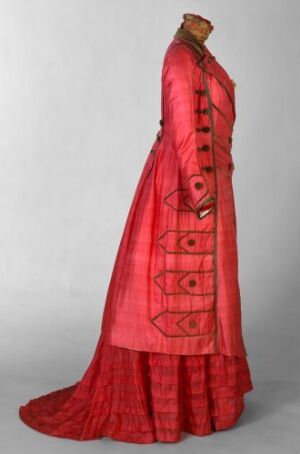  An elegant, full-length red dress with intricate darker red patterns on a mannequin, featuring a high neckline, full-length sleeved bodice with decorative buttons, and a flared skirt with a slight train. The garment possesses a monochromatic red aesthetic and an air of formal, vintage fashion.