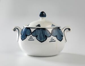  A glazed earthenware sugar bowl by Andreas Schneider with stylized blue leaf patterns and curved handles, set against a neutral background.