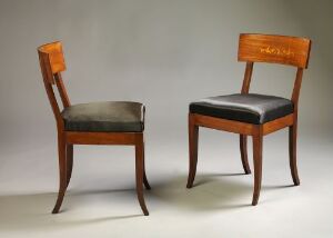  Two stylish wooden chairs with polished frames and dark grey upholstered seats; one features a padded backrest, while the other has a straight-edged wooden backrest, set against a soft grey background.