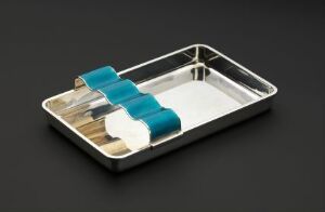  A stainless steel tray on a dark surface containing three wooden handles with teal fabric pads on top, suggestive of medical or dental instruments, under soft lighting with a reflective sheen.