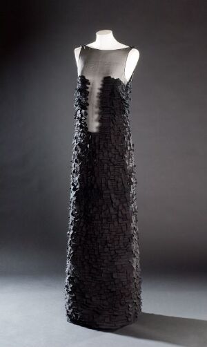  "The Art of Patchwork" by Armando E. Santos, a sophisticated, floor-length black dress made from frayed cotton patches and silk organza details on a mannequin against a gray background, embodying an elegant patchwork design.