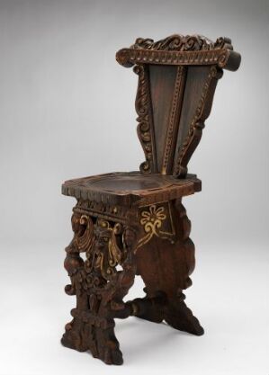  An elaborately carved antique wooden chair with a high decorative crest, ornate seat edges, twisted leg designs, and golden accents against a neutral gray background. Artistname and title: unknown.