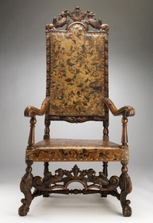  An antique high-backed chair named "Stol" by an unidentified artist, crafted from ash wood with turned post construction and pierce-carved patterns. The seat and backrest are upholstered in embossed golden leather with floral designs, set against a neutral grey background enhancing its ornate details.