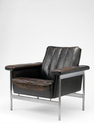  A modern chair designed by Sven Ivar Dysthe, featuring a chrome steel construction with dark brown oxhide upholstery on the seat, backrest, and armrests, set against a light grey background.