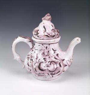  An ornately designed porcelain teapot with a pastel pink color palette, featuring raised decorative patterns, a swan-like spout, and a small figurine on the lid, against a soft gray background.