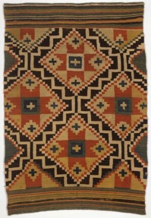  A handmade textile featuring a symmetrical geometric pattern with diamond and star shapes in earthy tones of brown, black, terracotta, tan, and dark teal, bordered with horizontal stripes at the top and bottom.