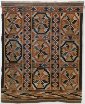  An image of a detailed, symmetrical handmade rug or tapestry with a warm brown background featuring columns of interlocking diamond motifs in burnt orange, black, blues, cream, and green. The patterns exhibit a tribal or cultural influence, with a complementary geometric border.