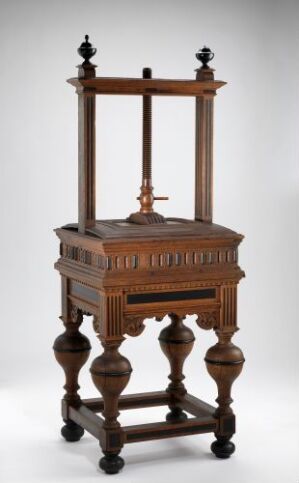  An antique Lintøypresse (linen press) made of oak with rich honey-brown tones, featuring turned legs, a chest with relief carvings and ebony inlays, and a distinctive upper structure with decorative beams and ebony finials, created by an unidentified artist.