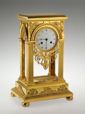  Antique gold-toned mantel clock with a white face and Roman numerals, featuring intricate openwork and scroll designs on the sides and base.