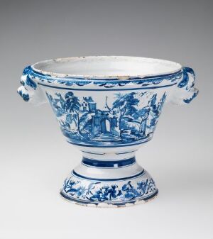  A white-glazed faience plant pot known as "Urte-Potte med Foed" with ornate hand-painted cobalt blue decorations depicting a landscape scene. It has a broad, rounded body with a flared foot and two handles on the sides, showcasing traditional European ceramic design. Artist name: Ukjent.