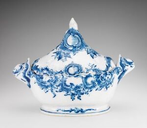  A white-glazed faience sauce boat with hand-painted cobalt blue floral patterns, crafted by Herrebøe Fajansefabrikk. The boat has a scrolled handle and a spout, reflecting a traditional and elegant design.