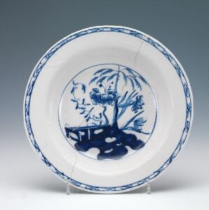  A traditional faience plate with a hand-painted cobalt blue decoration featuring a natural motif in the center and a patterned border, by an unknown artist.