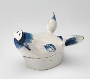 
 A handcrafted faience tableware piece by Herrebøe Fajansefabrikk with a white glaze and hand-painted cobalt blue decoration, featuring a playful, organic shape that resembles a stylized animal with protrusions reminiscent of fins or wings.