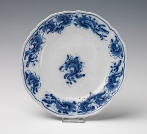 
 An antique white-glazed fajanse plate with hand-painted cobalt blue floral designs around the rim and a central blue motif, symbolizing classic design in tableware. Artist unknown.