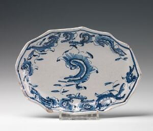  An octagonal-shaped decorative plate featuring intricate cobalt blue designs, including a central swirling wave motif, on a white background, set against a neutral gray backdrop. The rim of the plate is subtly scalloped, adding to its ornate appearance.