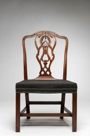  A traditional dark brown wooden chair with an intricately designed openwork backrest and a black upholstered seat, set against a light grey background.