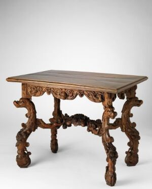  An antique rectangular walnut table by Grinling Gibbons, featuring an ornately carved edge, highly decorative apron, and sculptural legs with baroque high-relief carvings, set against a neutral background.