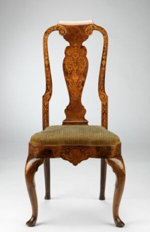  An antique wooden chair with ornate floral carvings on the backrest and cabriole front legs, upholstered with a golden-brown striped fabric, against a light grey background. Artist name and title are unknown.