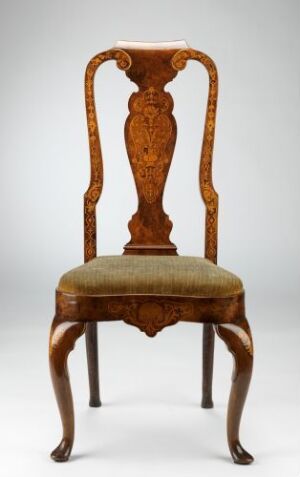  An ornate wooden chair with a rich, golden to reddish-brown color and a detailed backrest with a central carved motif. The chair has an upholstered seat in faded earth tones and elegantly curved legs ending in scrolled feet, set against a plain background.