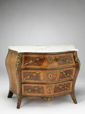  An antique wooden bombé commode with curved front and sides, featuring three drawers with floral inlays and brass handles, topped with a light-colored marble surface, against a gray background.