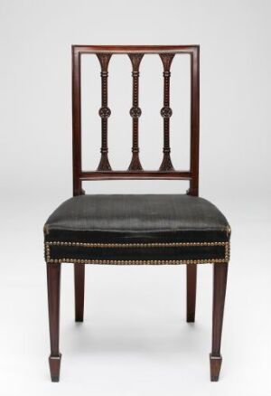  An elegant traditional wooden chair with a deep brown finish and three decorative vertical slats on the back, featuring a padded black leather seat with gold-colored nailhead trim along the edges.