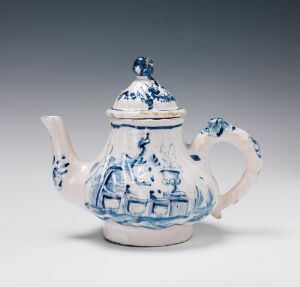  A blue and white ceramic teapot with a countryside scene design, featuring a rounded body, curved spout, loop handle, and a snug-fitting lid with a decorative knob.