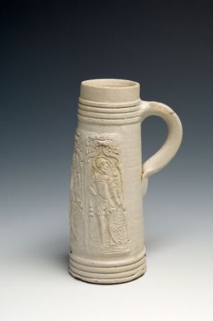  An off-white ceramic beer stein with a bas-relief design of a classical figure, standing against a blue-gray background.