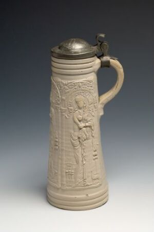  A stoneware stein named "Justitia" by Anno Knütgen, featuring a light grey salt-glazed body with darker grey relief of Justitia holding a sword and scales, accompanied by a cast pewter lid on a plain background.