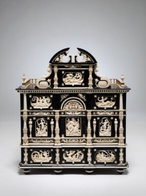  An intricate "Kabinettskap" designed by an unidentified artist, predominantly dark with detailed creamy white ivory carvings. The cabinet features a two-tiered structure with a distinct baroque flair, showcasing masterful woodworking techniques and ornate ivory figures set against the rich ebony.