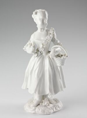  A porcelain figurine depicting a young woman in 18th-century attire, holding a flower basket, with intricate floral detail on her dress and an elaborate hairstyle, presented in a glossy white finish.