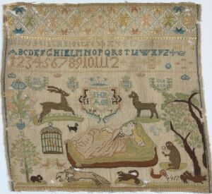  A photograph of an antique-looking embroidered sampler, featuring an uppercase alphabet at the top, numerals 1 through 12 at the center, a coat of arms with birds in the middle, and various animals and a domestic scene depicted at the bottom, all rendered in soft, muted colors on aged beige fabric.