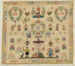  An antique sampler featuring a variety of motifs including birds, flowers, and geometric patterns, stitched in muted colors on aged beige fabric, with a central symmetrical composition showing two large birds facing each other above a basket with a tree-like design and smaller creatures on its branches. Artistname and title are unknown.