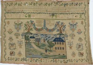  Antique handcrafted textile depicting a pastoral scene with a large house and barn, a river or road with a bridge, surrounded by various plants and trees, framed by symmetrical floral decorative borders. The colors are muted and include shades of blue, red, green, and yellow on a light beige background.