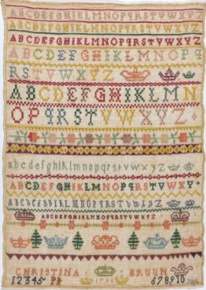  An antique embroidered sampler featuring multiple rows of stitched alphabets and numbers in various colors on an off-white background, with decorative elements such as flowers, birds, and hearts interspersed throughout.