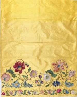  Embroidered golden-yellow fabric with a crinkled texture, decorated with a colorful band of stylized florals and foliage along the bottom edge.