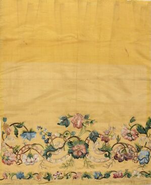  Antique-style yellow fabric with a detailed floral embroidery pattern in pastel colors along the bottom edge.