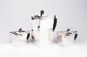  A modern silver tableware set by Jacob Tostrup Prytz, comprising a tall coffee pot with a black handle grip in the center, flanked by a smaller sugar bowl and creamer, all displayed against a white background.