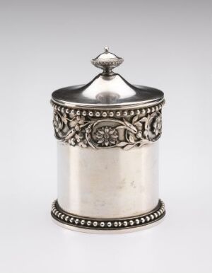  A silver metal canister with embossed floral decorative band and a beaded base, topped with a matching finial-lid against a light grey background. Artistname and title are unknown.