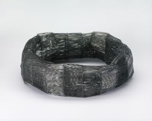  An oxidized silver bracelet in riveting technique, titled "Sobel" by artist Toril Bjorg, featuring a dark color palette and richly textured surface with various patterns, displayed against a plain background.