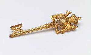  An ornate gilded bronze key known as "Kammerherrenøkkel" created by an unidentified artist, featuring open-worked decoration and an elaborate handle set against a neutral background, reflecting its luxurious and ceremonial design.