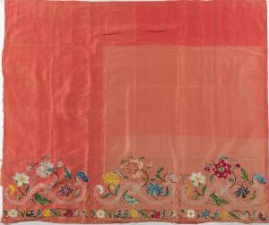 Alt-Text: A translucent coral-pink textile with a layered sheer rectangle along one edge and a bottom border adorned with vibrant, intricate embroidery of multicolored flowers in blues, purples, yellows, greens, and pinks. Artistname and title are unknown.