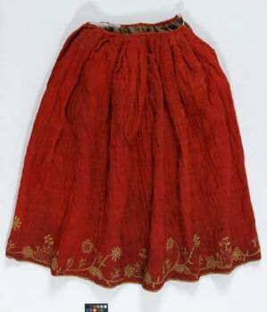  A full, mid-length red skirt with gathered waist and intricate golden floral embroidery near the hem, displayed against a neutral background.