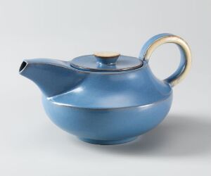  A glossy blue ceramic teapot with a wooden knob and a golden accent on the handle, placed against a neutral gray background.