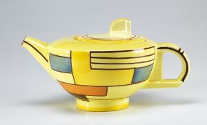  A ceramic teapot designed by Eva Striker Zeisel with a bright yellow body, featuring geometric decorations in pale blue, black, teal, and terracotta. The teapot has a spherical shape, a pale yellow lid with a rectangular handle, and a curved handle and spout with black accent lines. The design conveys a sense of modern elegance and playfulness.